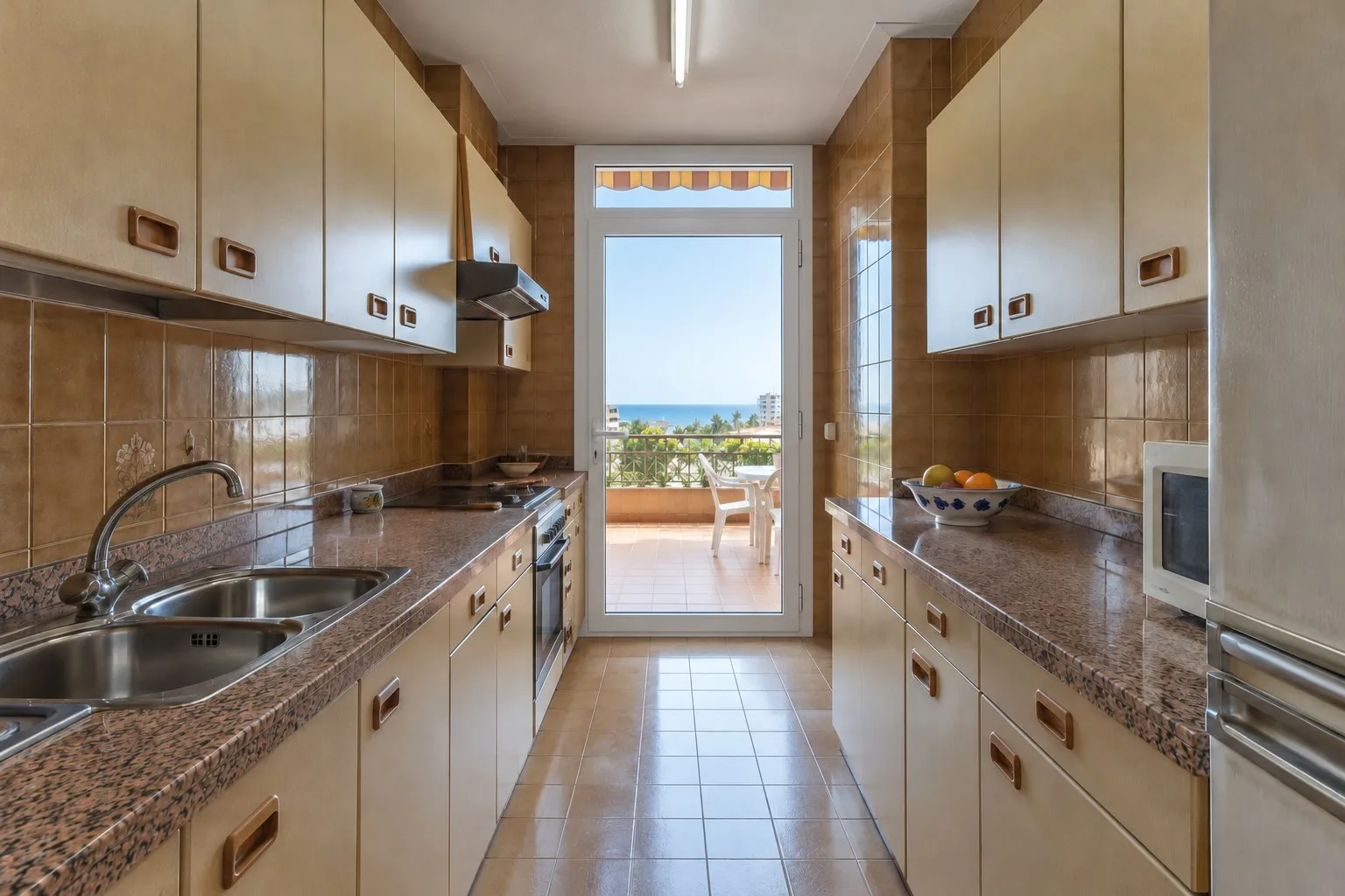 Cocina alargada con muebles de formica y encimera de granito en Benalmádena Costa, antes de la reforma